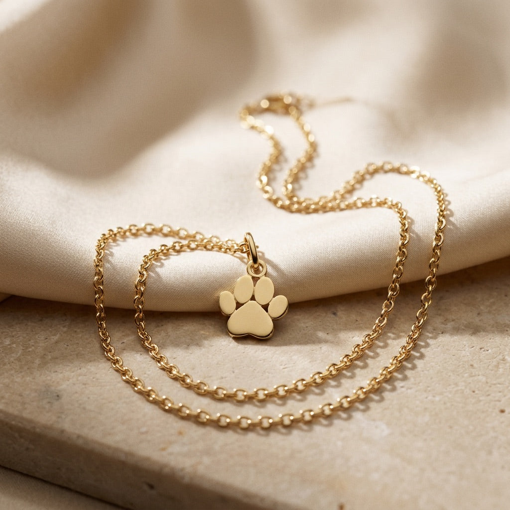 Gold necklace with a paw print pendant on a beige fabric background