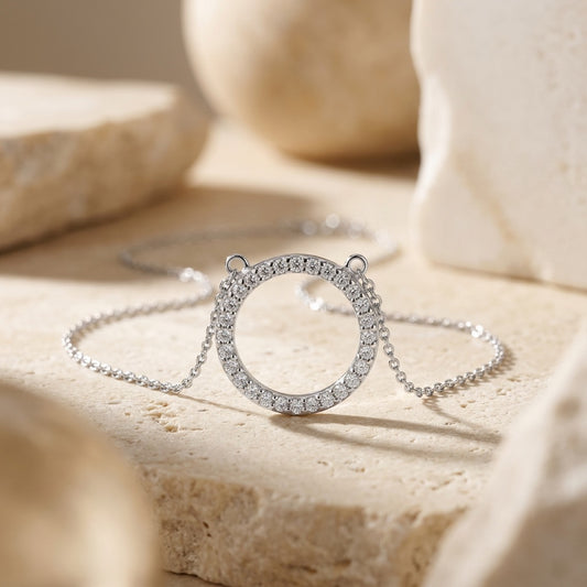 Silver necklace with circular pendant on a beige surface