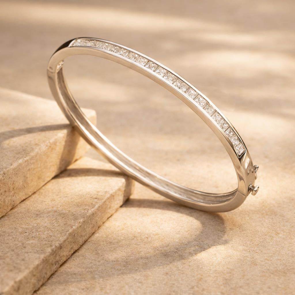 A Square Channel Set Bangle with Cubic Zirconia with diamonds on a beige stone surface