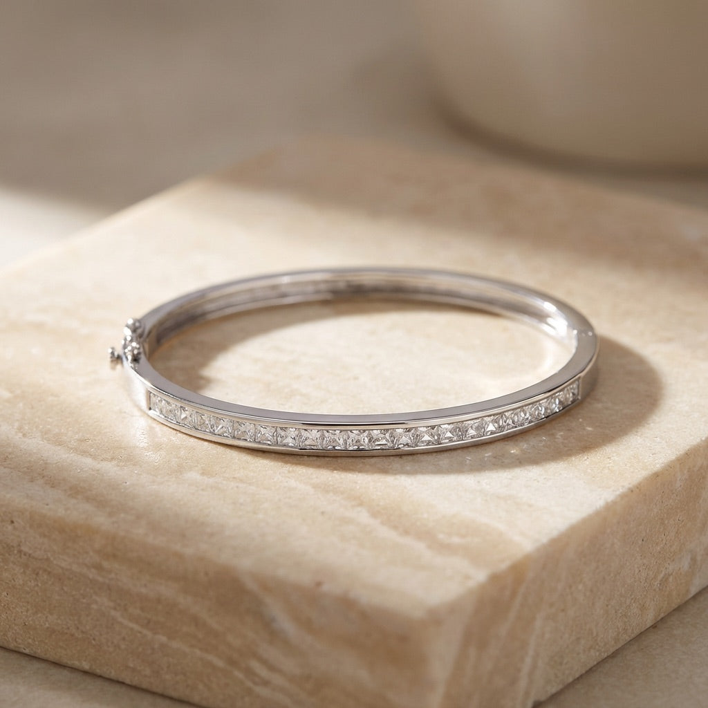 Silver bracelet with small diamonds on a beige stone surface