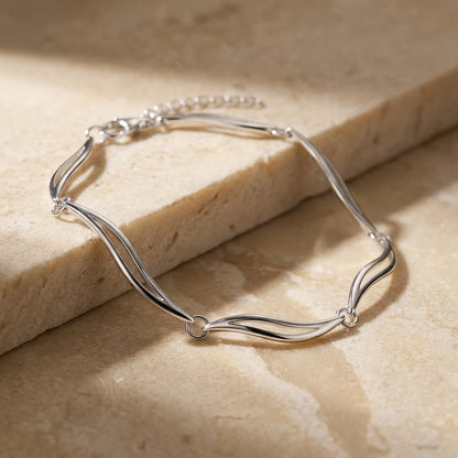 Alpha Bijoux | Silver bracelet on a beige stone surface