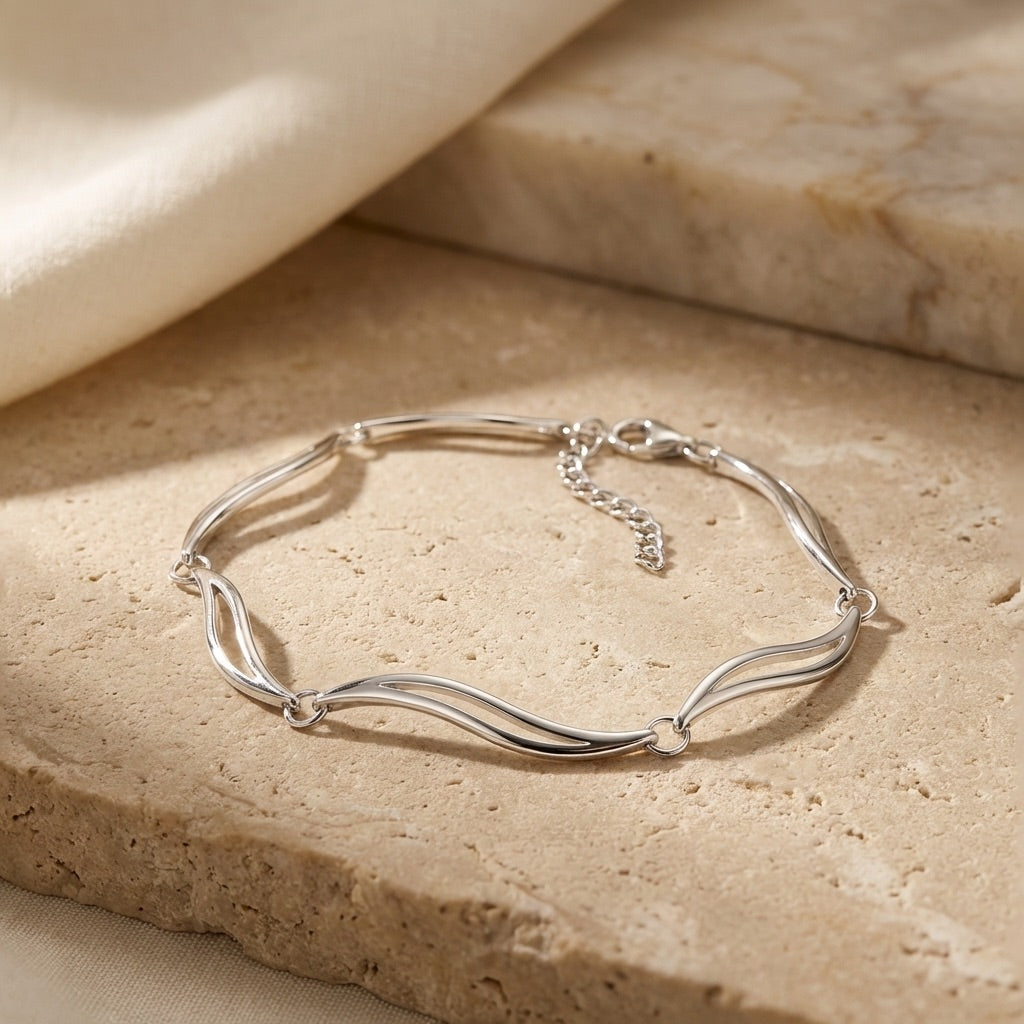 Silver linked leaves bracelet on a beige stone surface