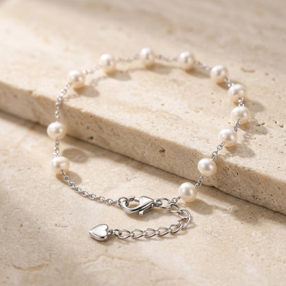 Pearl bracelet with silver clasp on a light wooden surface