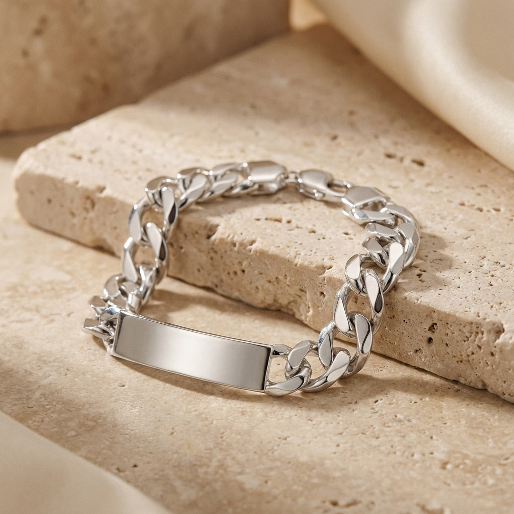 Silver chain bracelet with a nameplate on a beige stone surface