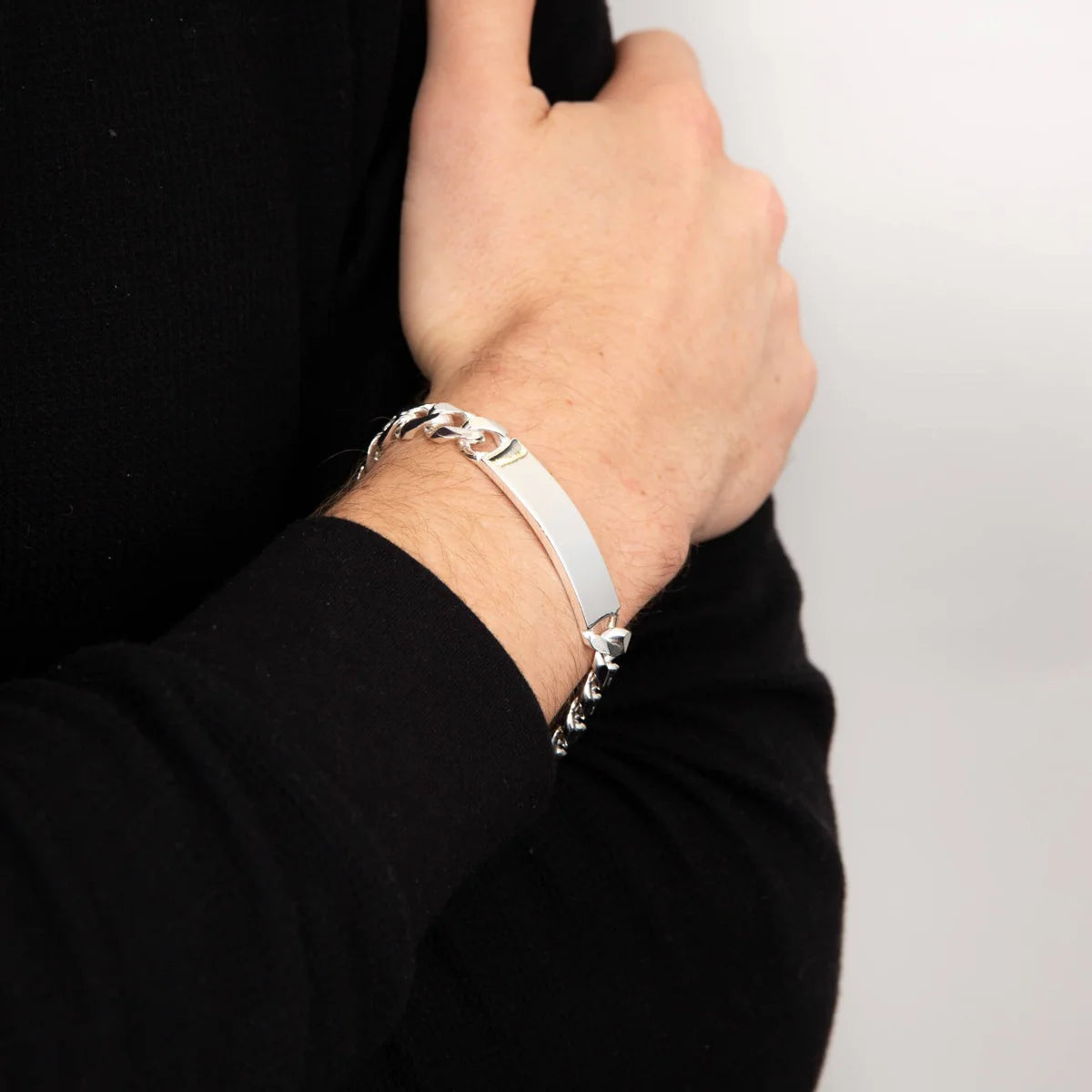 Silver bracelet on a person's wrist against a plain background