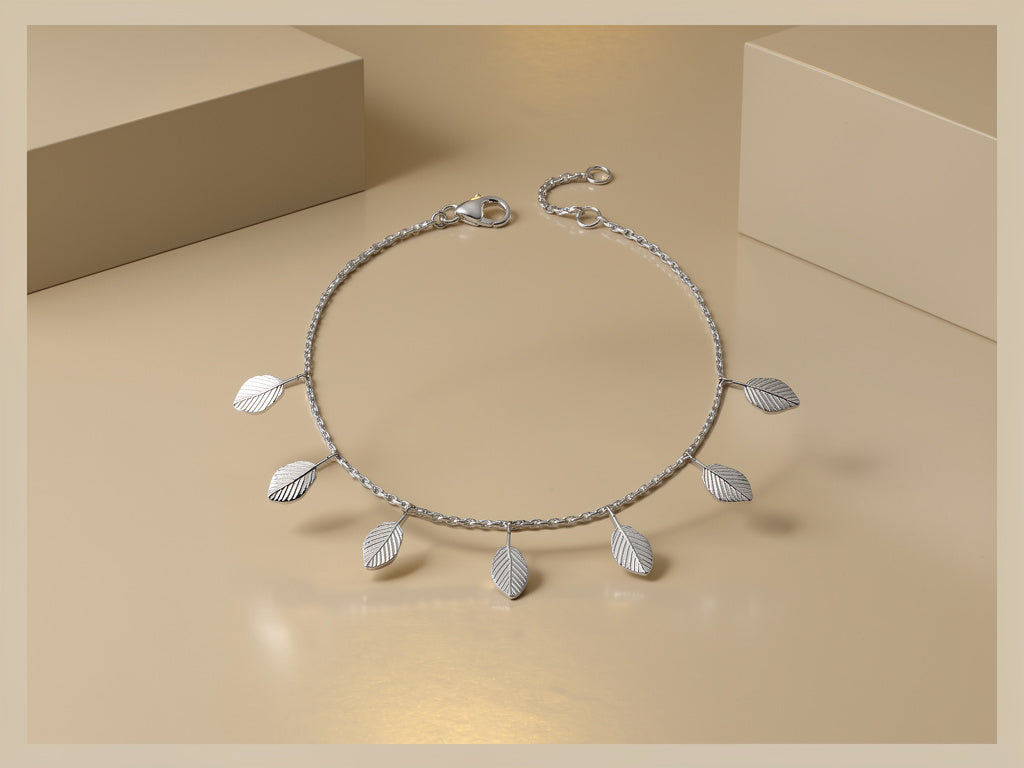 Silver necklace with leaf pendants on a beige background