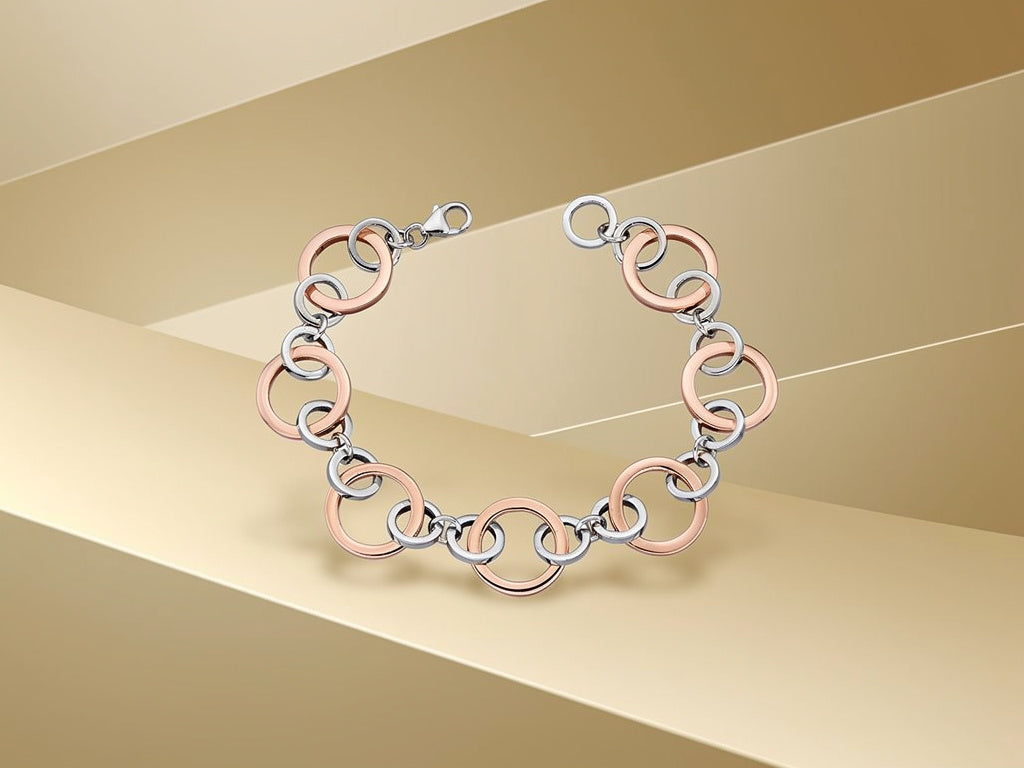 Bracelet with interlocking rings in rose gold and silver on a beige background