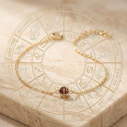 Gold bracelet with a red gemstone on an engraved zodiac wheel