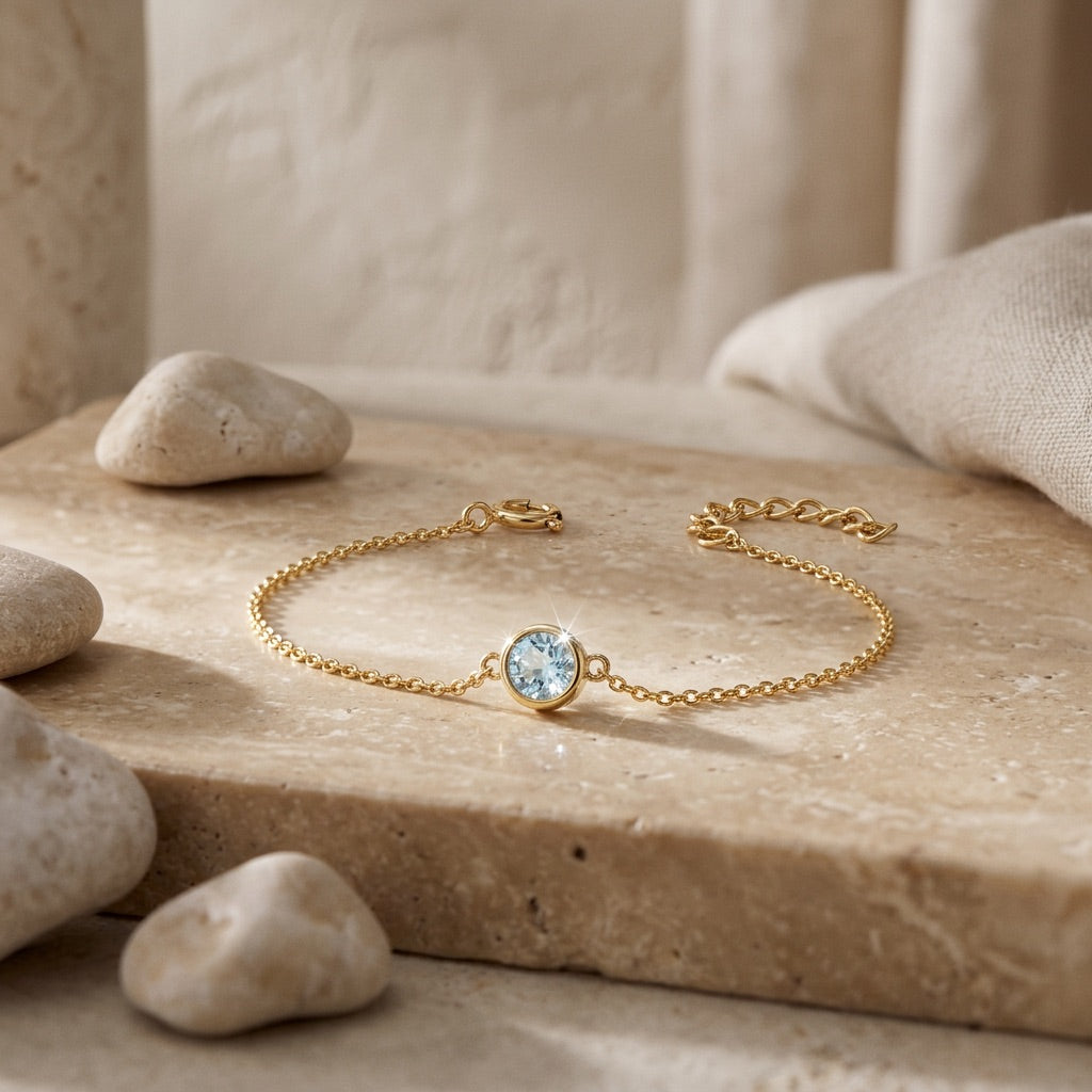 Gold bracelet with a round gemstone on a stone surface