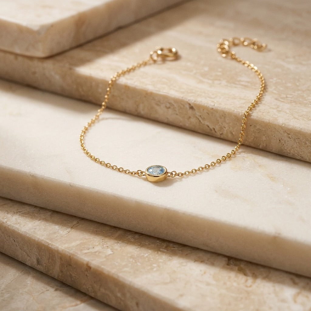 Gold bracelet with a gemstone on a marble surface