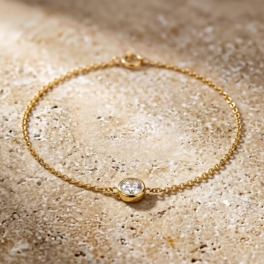 Gold bracelet with a diamond on a textured beige surface