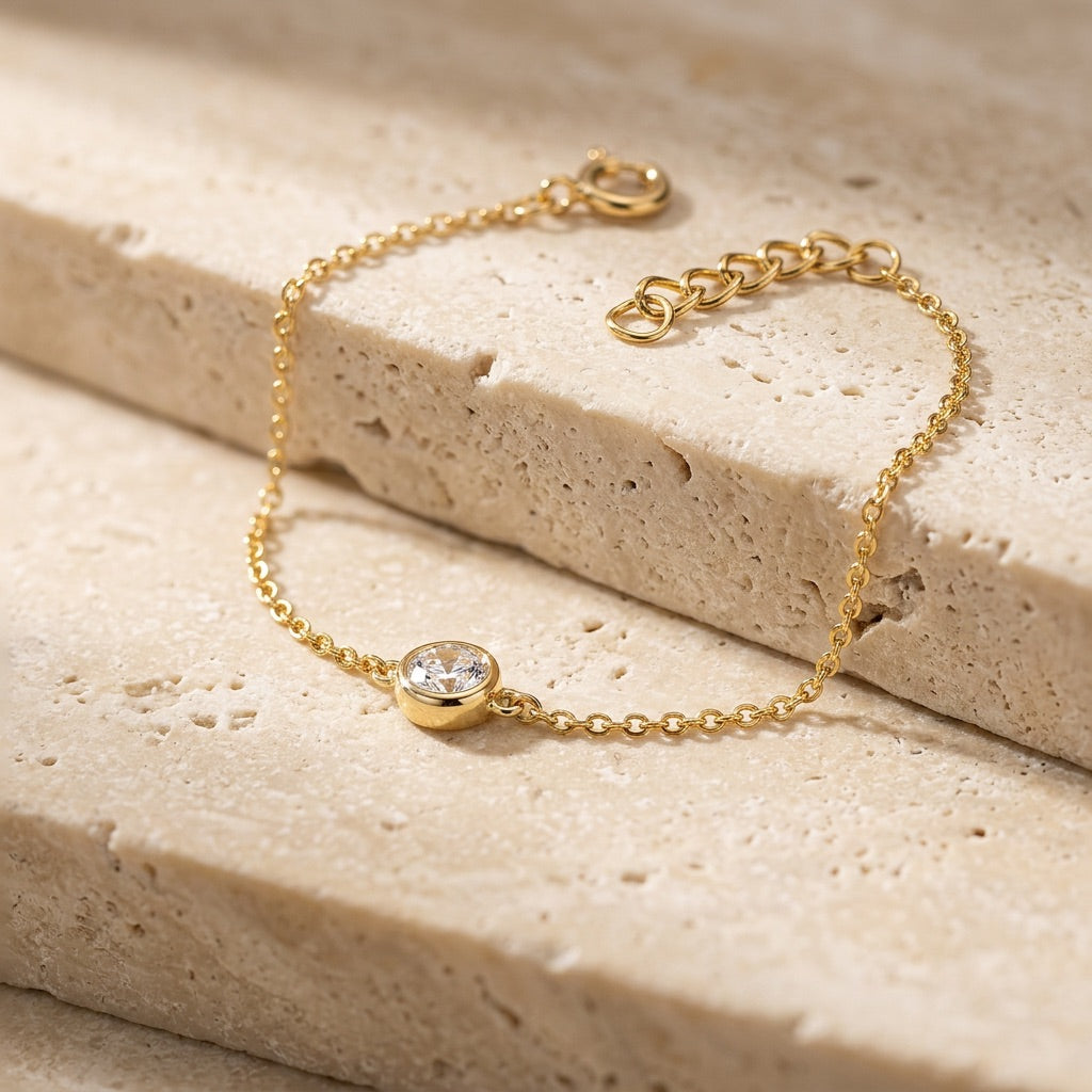 Gold bracelet with a diamond on a beige stone surface