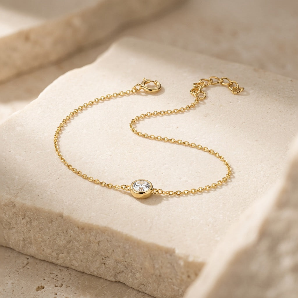 Gold bracelet with a diamond on a beige stone surface