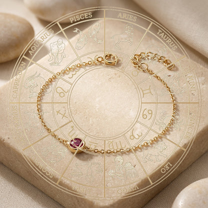 Gold bracelet with a red gemstone on a zodiac wheel