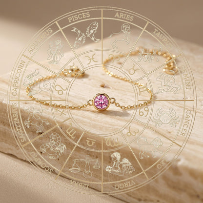 Gold bracelet with a pink gemstone on an astrological chart