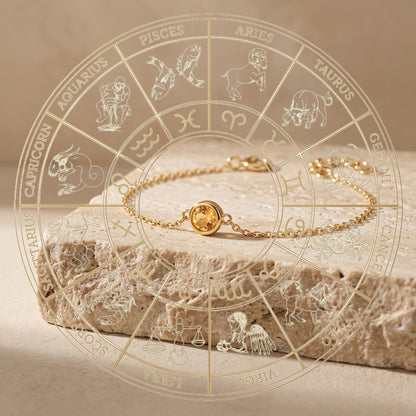 Gold ring with a yellow gemstone on a stone surface with zodiac signs.
