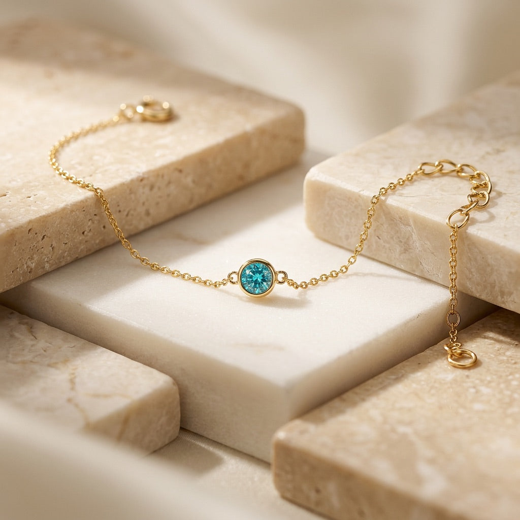 Gold bracelet with a blue gemstone on a beige stone surface