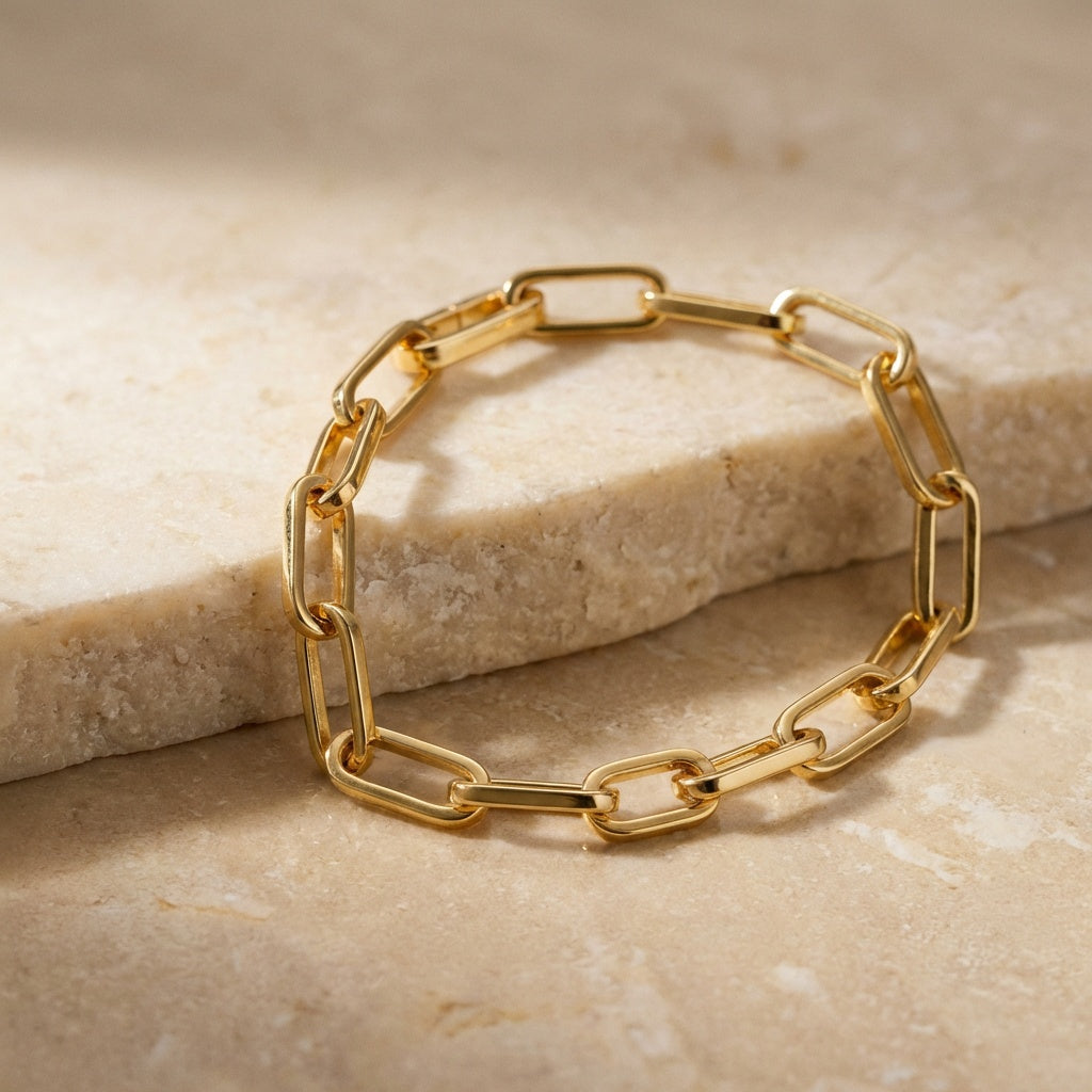 Gold chain bracelet on a beige stone surface