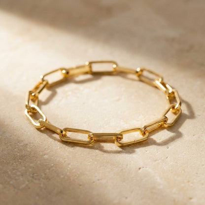 Gold chain bracelet on a beige surface