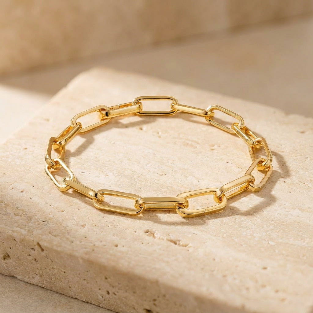 Gold chain bracelet on a beige stone surface