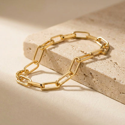 Gold chain bracelet on a beige stone surface