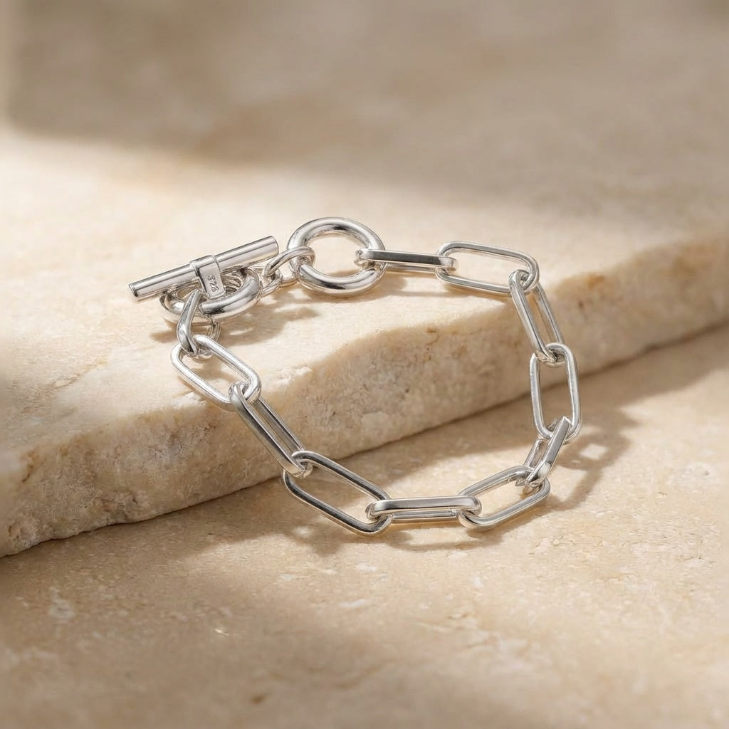 Silver chain bracelet on a beige stone surface