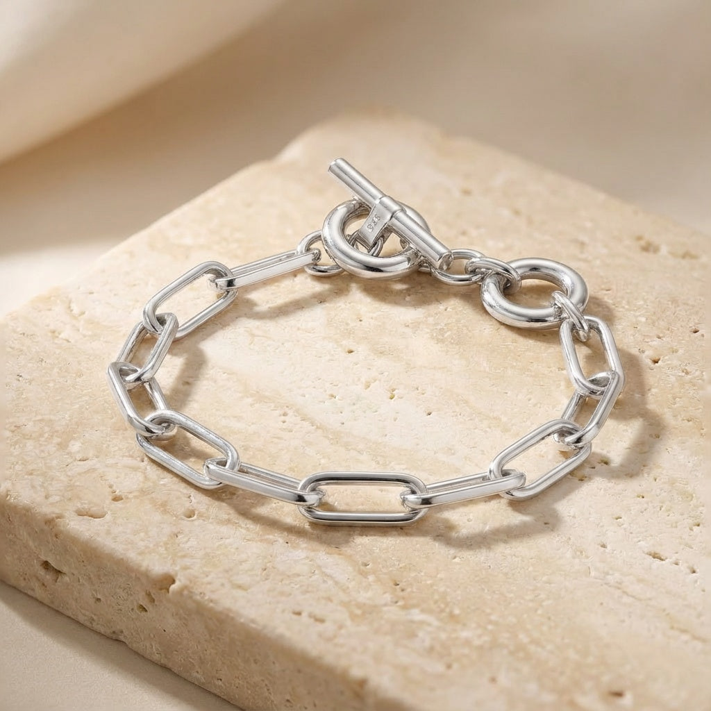 Silver chain bracelet on a beige stone surface