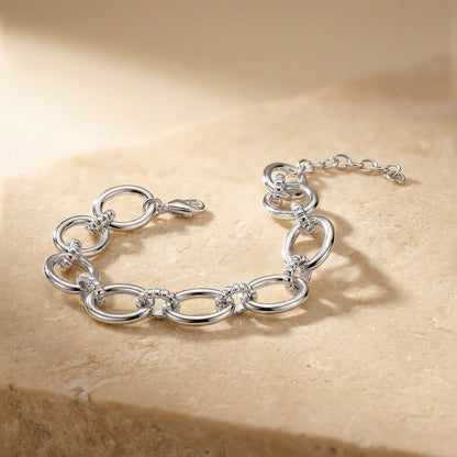 Silver chain bracelet on a beige stone surface