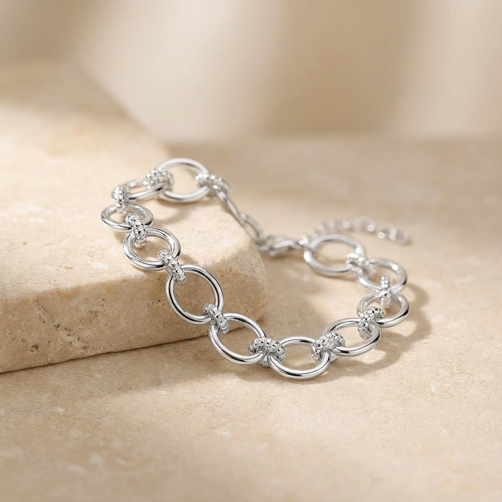 Silver chain bracelet on a beige stone surface