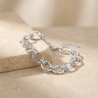 Silver chain bracelet on a beige stone surface