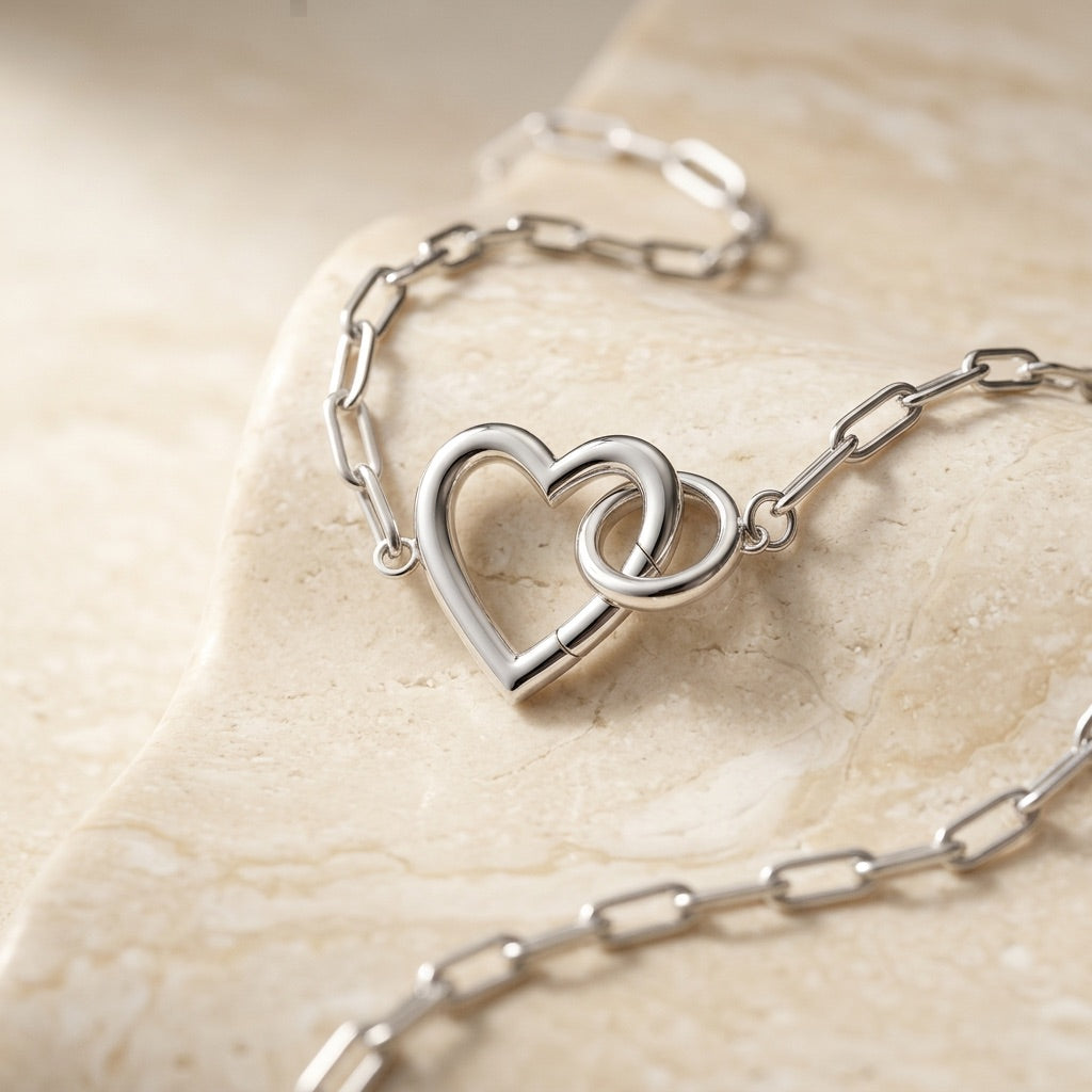 Silver bracelet with a heart-shaped clasp on a beige stone surface