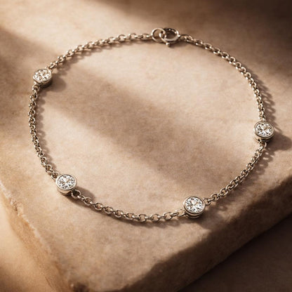 Silver bracelet with small round crystals on a beige stone surface