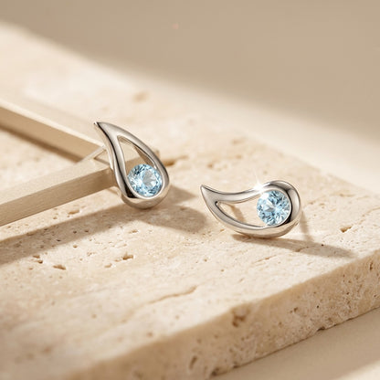 Silver earrings with blue gemstones on a beige surface
