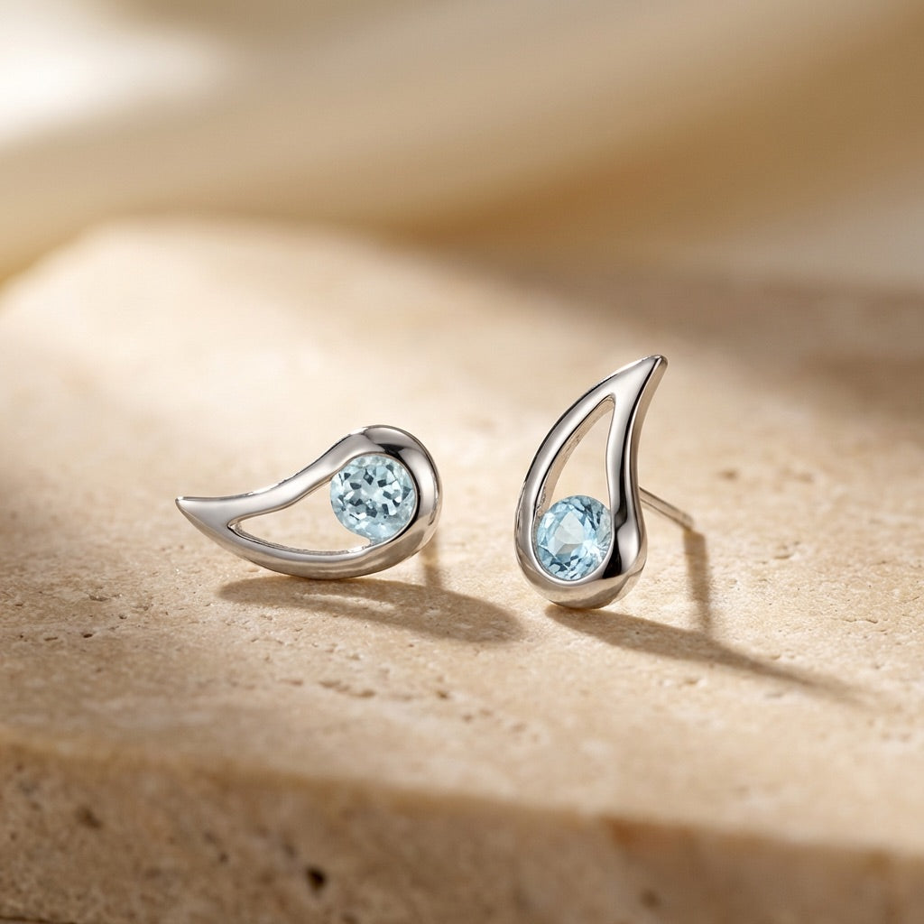 Silver earrings with blue gemstones on a beige surface