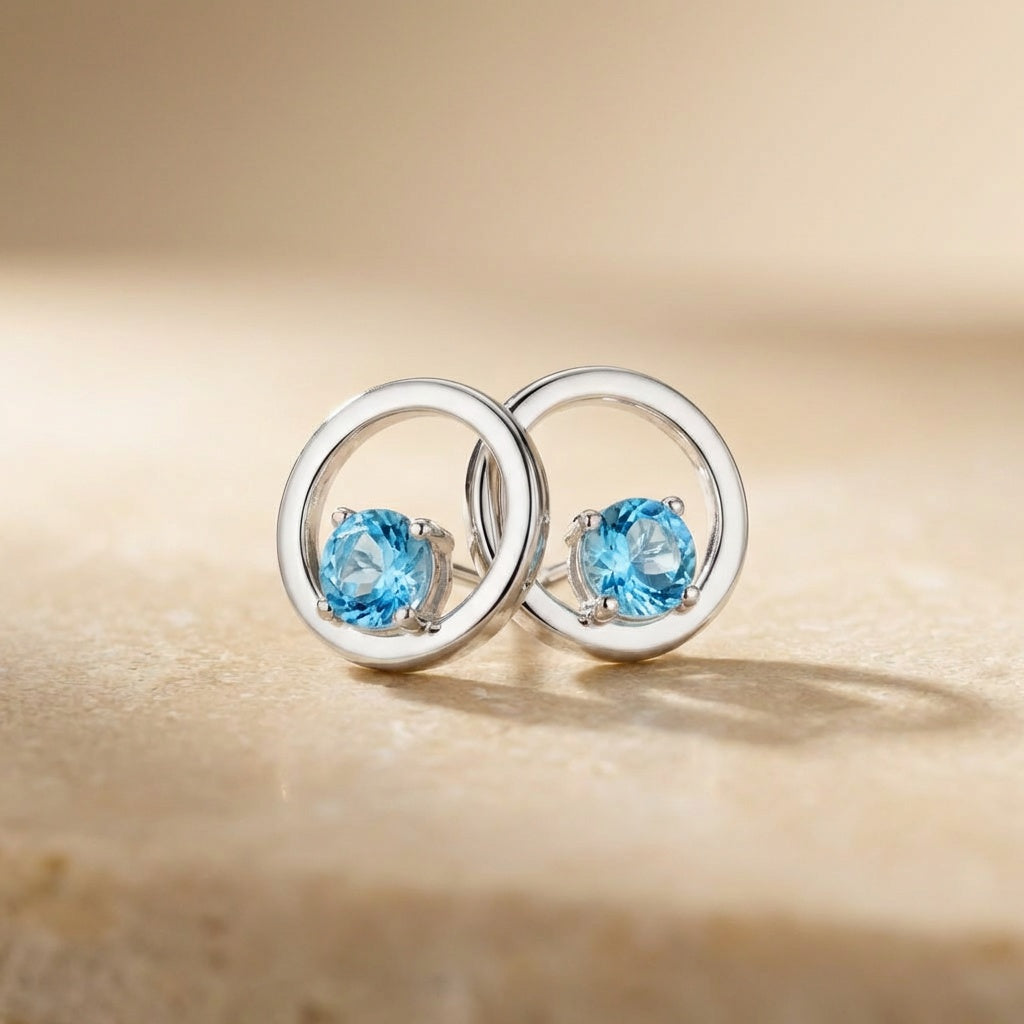 Silver earrings with blue gemstones on a beige background