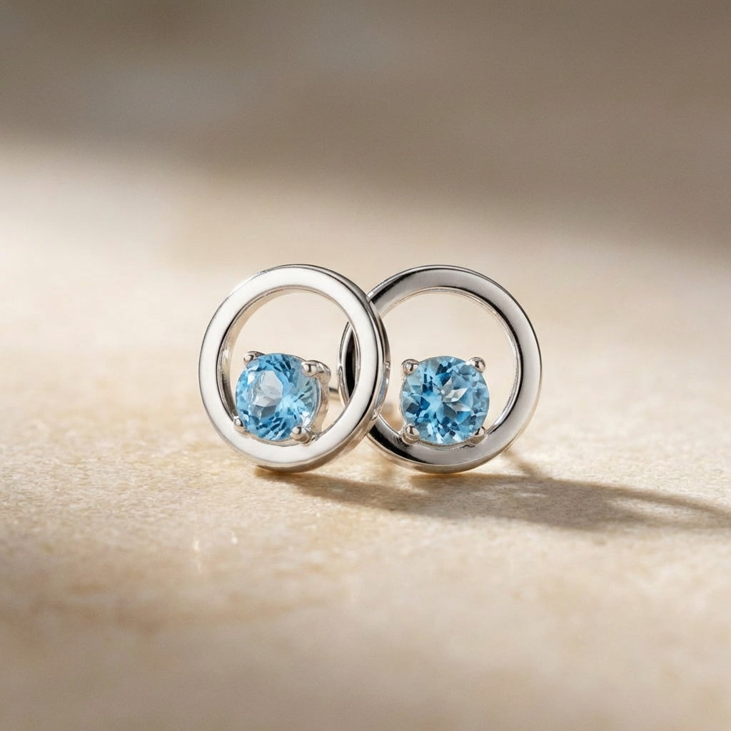Silver earrings with blue gemstones on a beige background