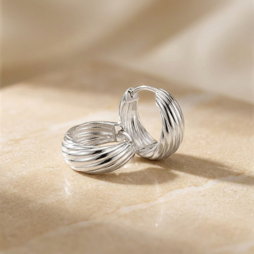 Pair of silver hoop earrings on a beige surface