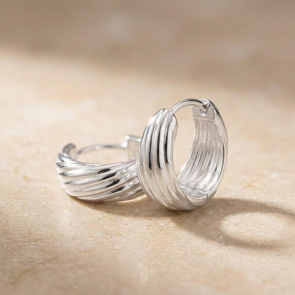 Silver hoop earrings on a beige surface
