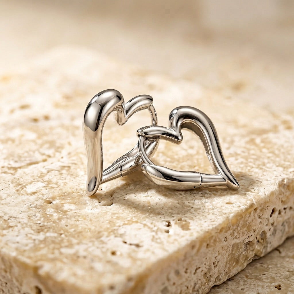 Silver cufflinks shaped like interlocking hearts on a textured stone surface