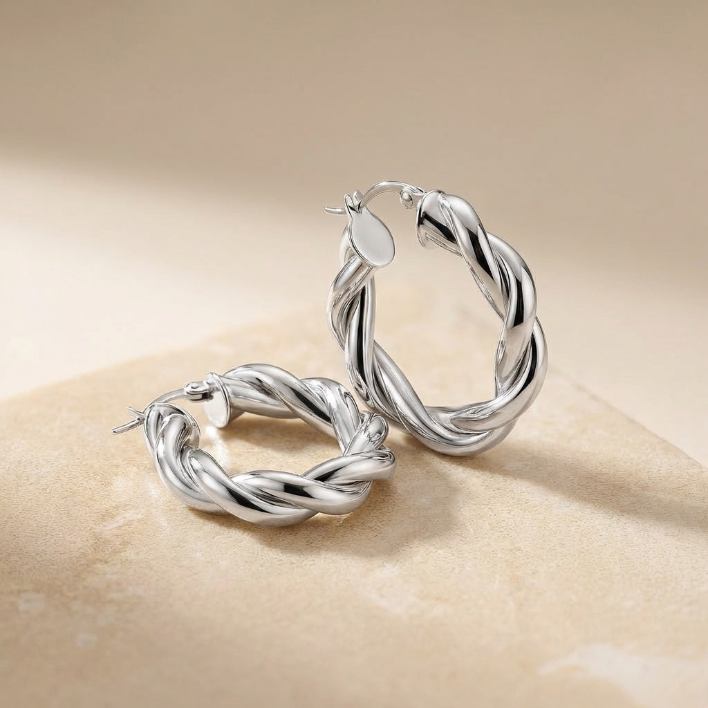 Pair of silver hoop earrings on a beige background