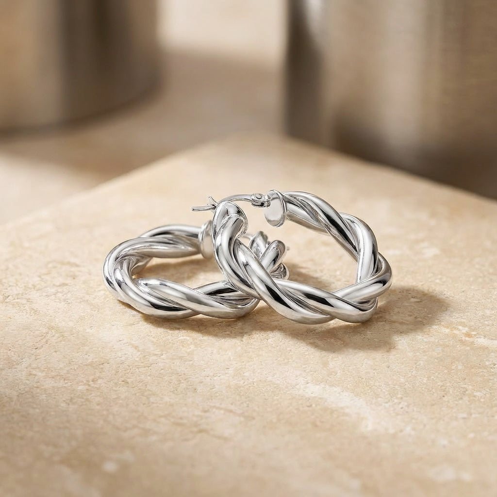 Pair of silver hoop earrings on a beige surface