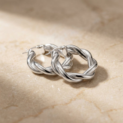 Silver hoop earrings on a beige marble surface