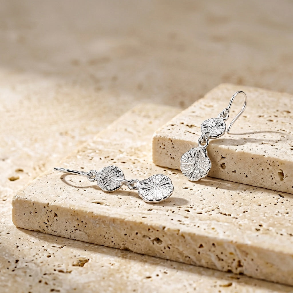 Silver earrings on a textured stone surface