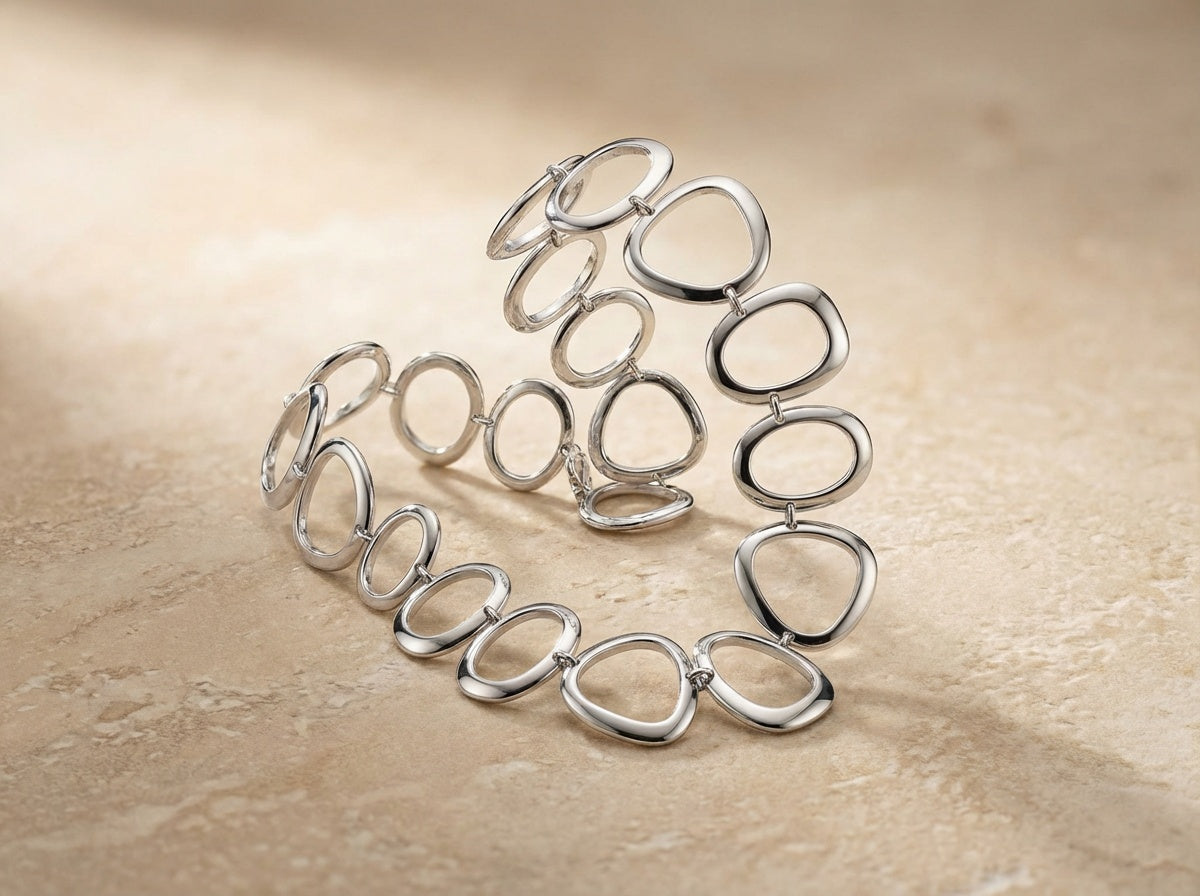 Silver bracelet with interlocking rings on a beige background