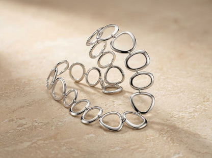 Silver bracelet with interlocking rings on a beige background