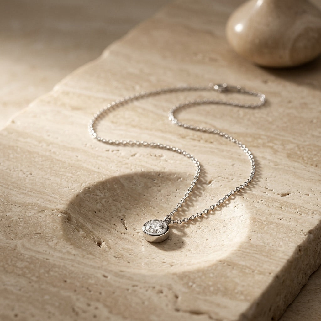 Silver necklace with a pendant on a textured stone surface
