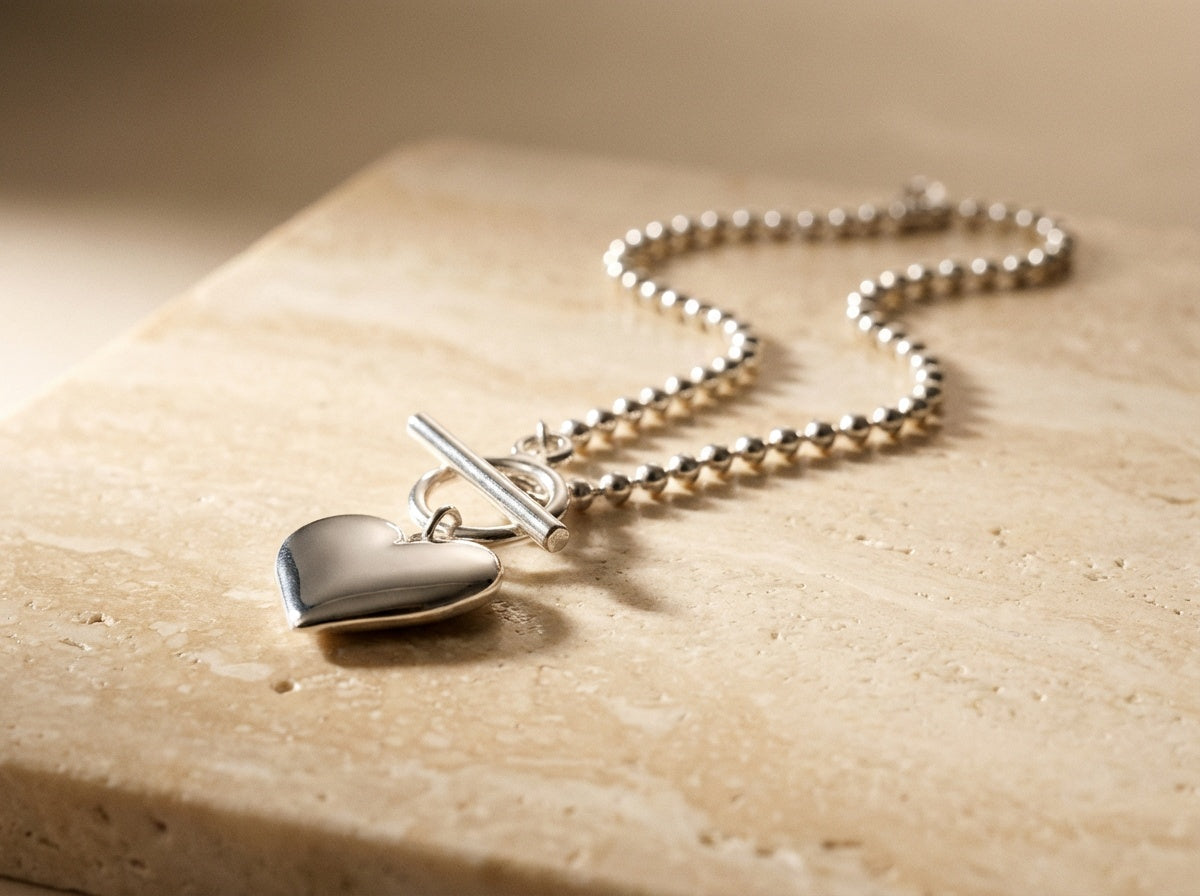 Silver heart-shaped pendant necklace on a textured surface