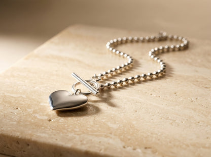 Silver heart-shaped pendant necklace on a textured surface