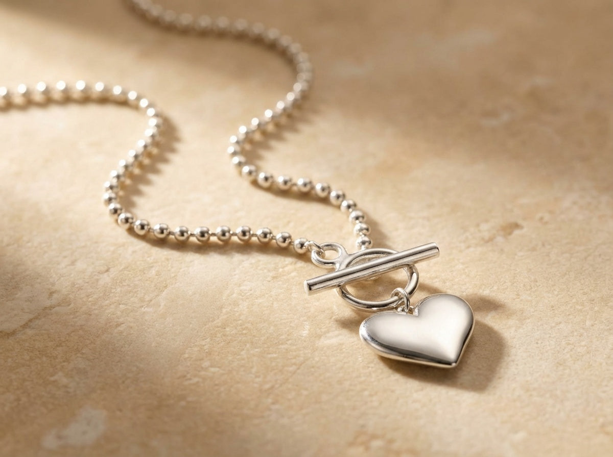 Silver necklace with a heart pendant on a beige background