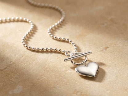 Silver necklace with a heart pendant on a beige background